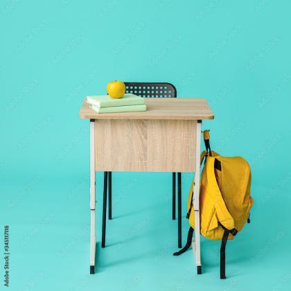 school desk with books, and apple and a backpack