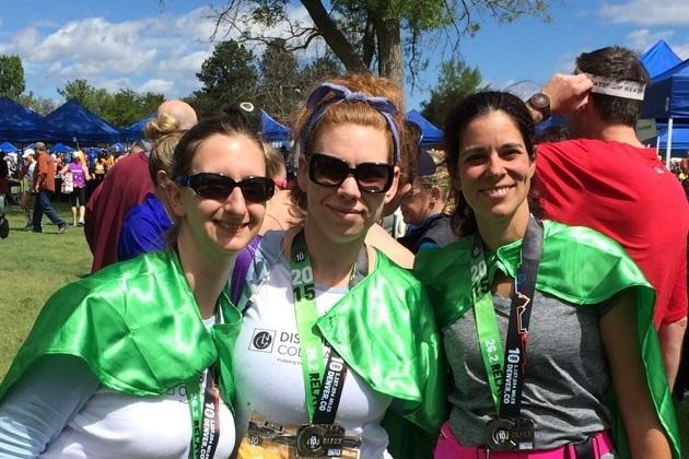 photo of 3 female runners with green Disability Law Colorado capes and colfax marathon relay medals around their necks