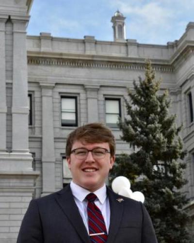 smiling young white man in a suit infant of the Colorado State Capitol Building