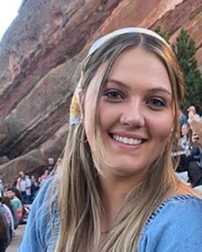 picture of Rachel Gärlick smiling at Red Rocks Amphitheater wearing a blue shirt and scarf in  