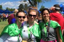 photo of 3 female runners with green Disability Law Colorado capes and colfax marathon relay medals around their necks