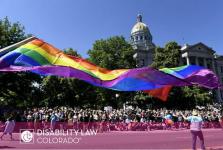 picture of Colorado pride parade with a big PRIDE flag and parade goers