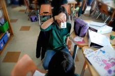 student in a classroom holding up a flashcard